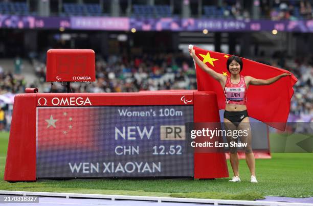 Gold medalist, Xiaoyan Wen of Team People’s Republic of China, poses for a photo beside the scoreboard after setting a personal best time of 12:52...
