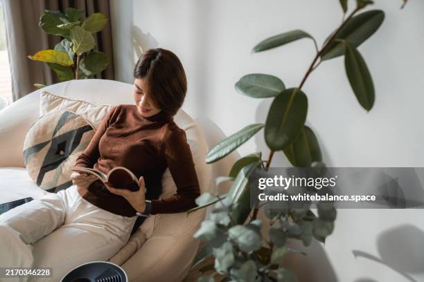 asian woman turning on air purifier in a smart home - luchtvochtigheid stockfoto's en -beelden