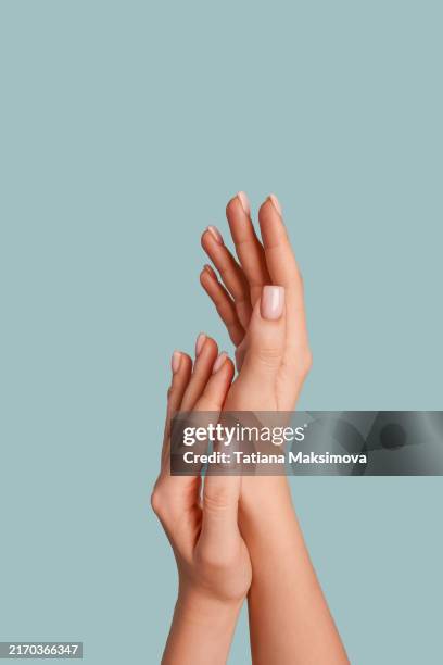 hands with a beautiful soft pink manicure on a blue background. - fingernagel stock-fotos und bilder