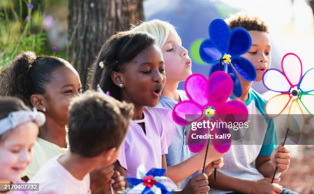 multiracial children in park playing with pinwheels - moinho de papel imagens e fotografias de stock