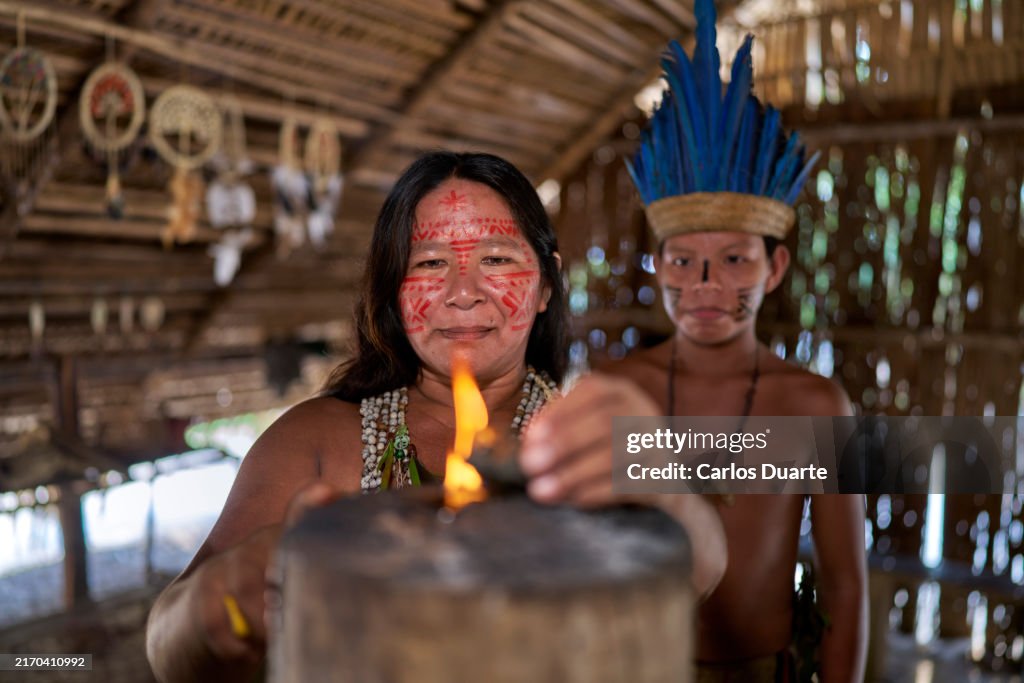 Eine indigene Frau aus dem Amazonasgebiet zündet mit ihrem Sohn ein Feuer an, um das Ayahuasca-Ritual zu beginnen