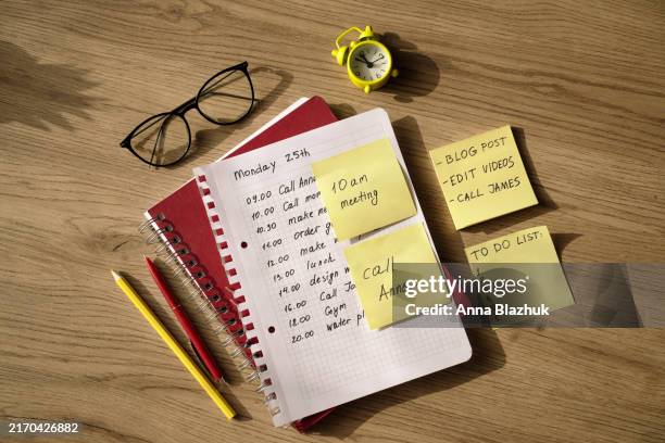 sticky yellow notes with tasks, note pad with to-do list on working desk. office supplies, eyeglasses, pencils, clock on wooden surface - to do list stock pictures, royalty-free photos & images