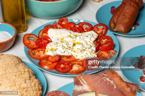 preparing a mediterranean table setting with bread, tomatoes and cheese - burrata stock pictures, royalty-free photos & images