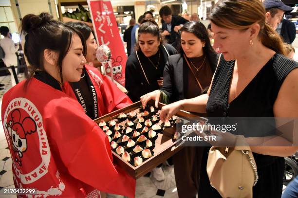 This photo taken on September 7, 2024 shows a customer trying peaches from Japan's Fukushima prefecture, which went on sale at luxury department...