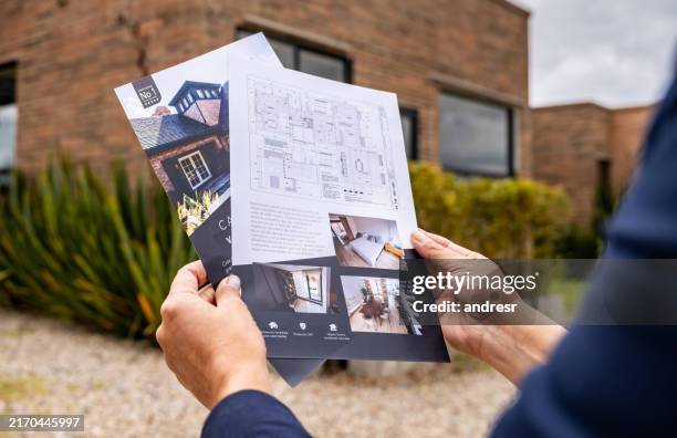 real estate agent holding brochures of a house for sale - brochure stock pictures, royalty-free photos & images