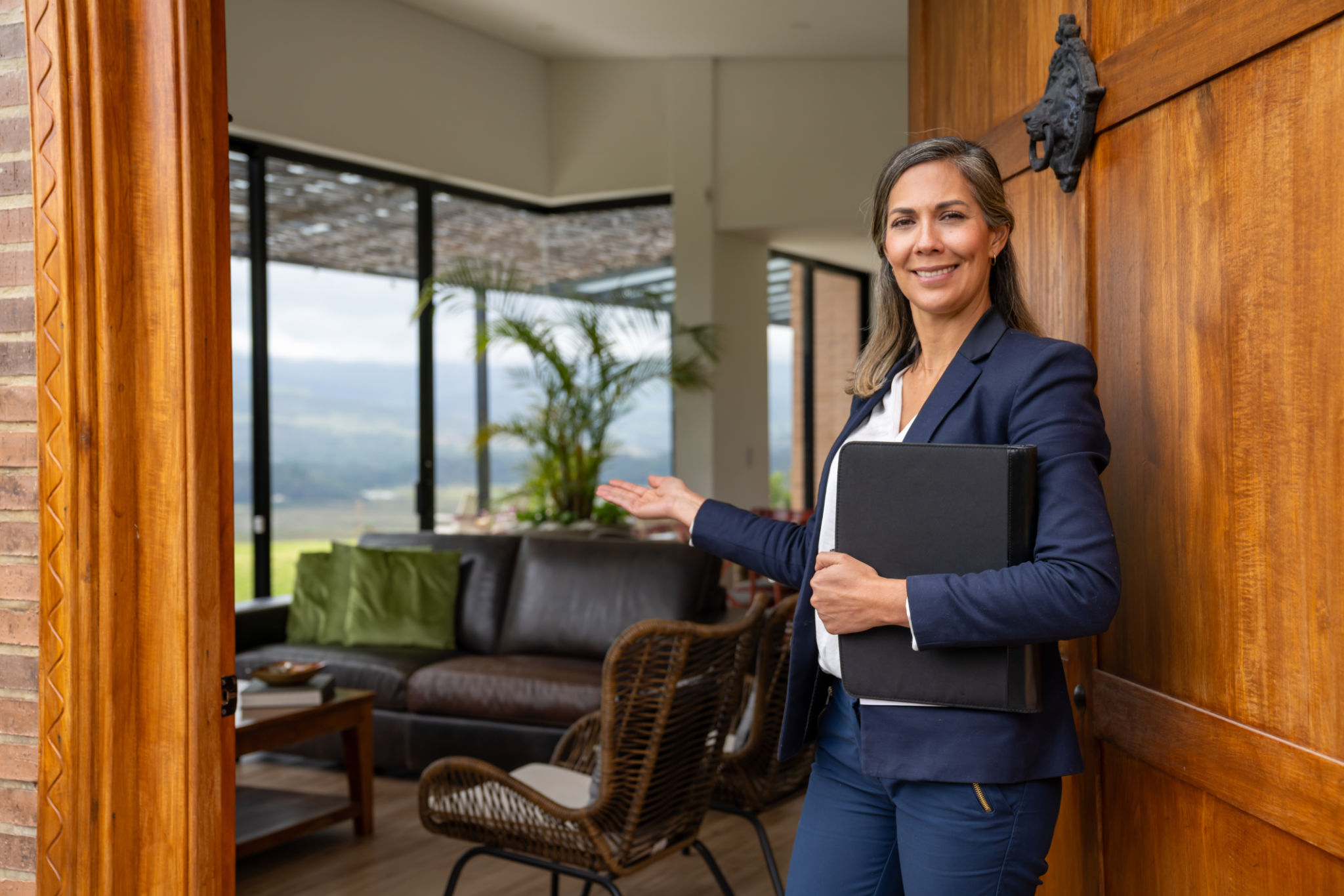 Real estate agent welcoming clients for a house showing and looking at the camera smiling - POV concepts