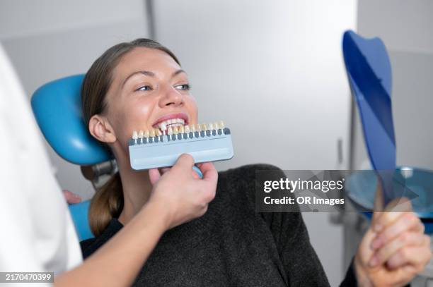 doctor showing dental implant to female patient at dentist's office - implante dentário imagens e fotografias de stock