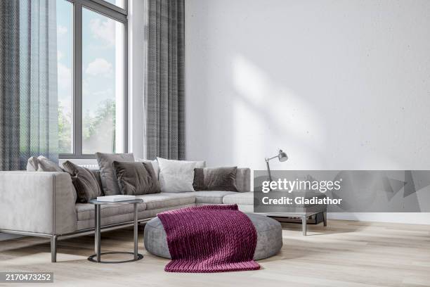 front view of a cozy, elegant, and modern living room with gray sofa, a pouffe, windows with curtains, and decoration - side table stock pictures, royalty-free photos & images