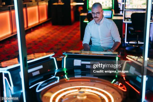 un hombre pasa tiempo en un casino - casino interior fotografías e imágenes de stock