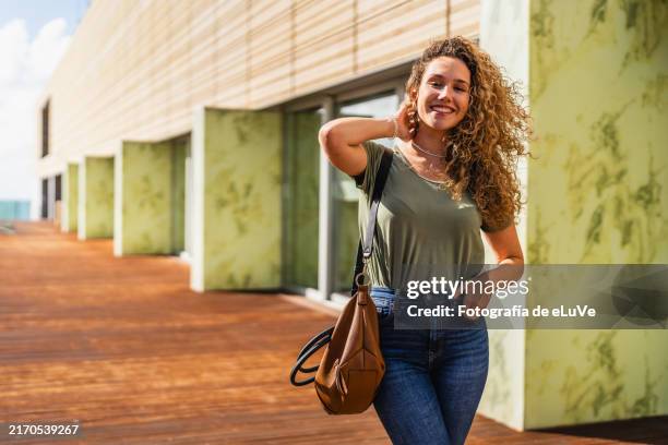 smiling businesswoman posing outside the office building - cabello ondulado fotografías e imágenes de stock