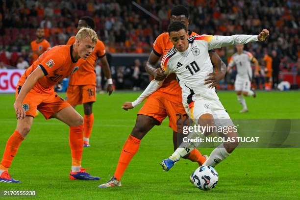 Germany's midfielder Jamal Musiala fights for the ball with Netherlands' defender Jan Paul van Hecke and Netherlands' defender Denzel Dumfries during...