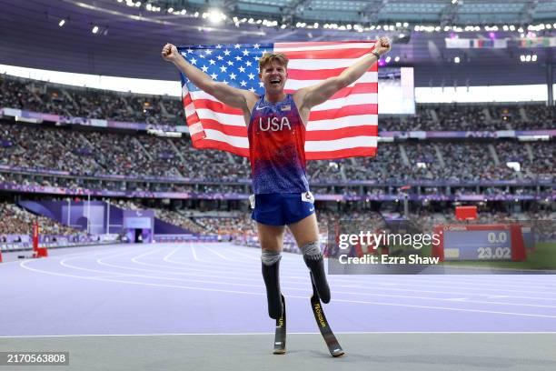 Hunter Woodhall of Team United States celebrates with the flag of United States after winning a gold medal in the Men's Para Athletics 400m T62 Final...
