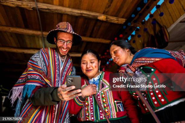 hombre turista mostrando el teléfono móvil chinchero indígena en un mercado, en el distrito de chinchero, perú - cultura tribal americana fotografías e imágenes de stock