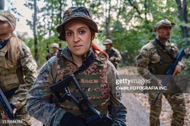 unité de soldats armés marchant dans une zone boisée après avoir terminé leur formation militaire - formation militaire photos et images de collection