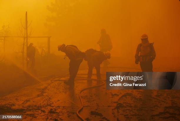 Firefighters are overcome with smoke while battling a house fire as the Line fire burns on September 10, 2024 in Running Springs, California.