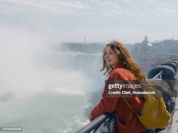 woman looking at niagara waterfall with awe - niagarawatervallen stockfoto's en -beelden