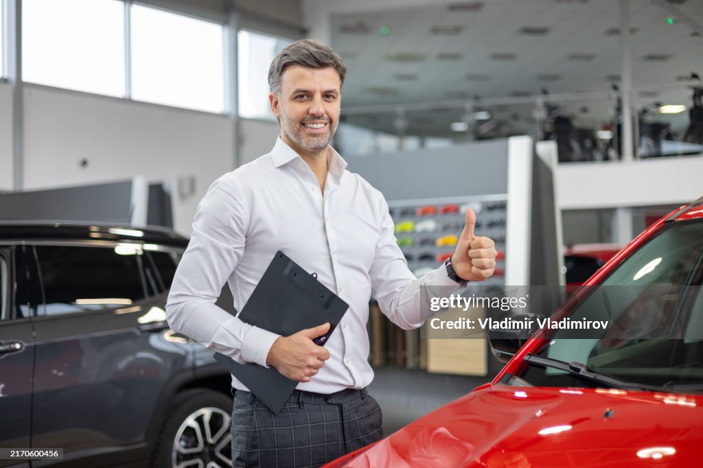 Salesman gives thumbs up in car showroom