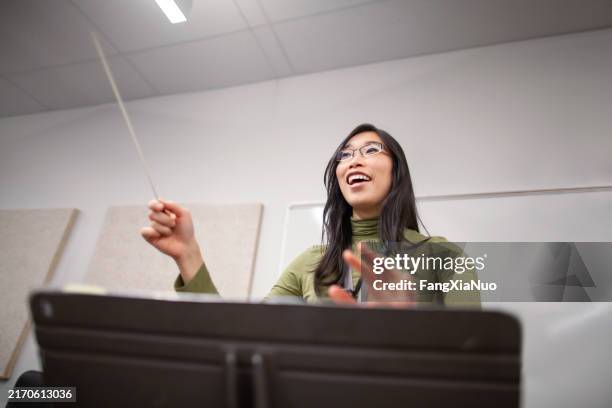 porträtansicht von bandlehrer lehrer dirigent hände leiten musikaufführung orchester von junior high school teenager schüler üben im schulklassenzimmer zusammen - dirigent stock-fotos und bilder