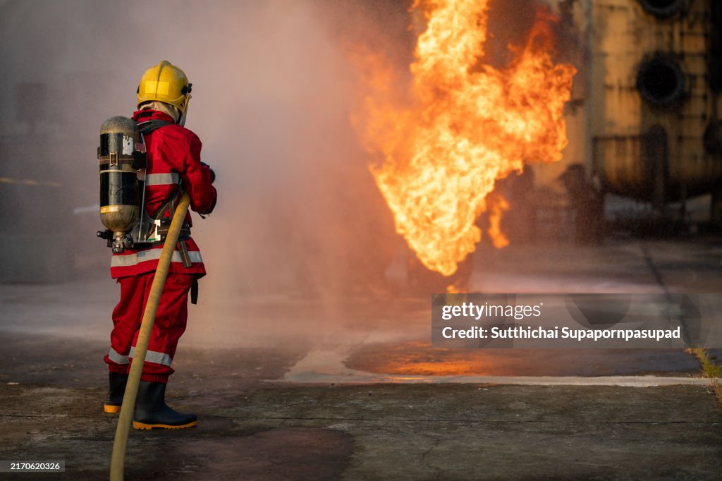 Fireman fighting raging inferno with full protective gear, focused on extinguishing fire and saving lives amidst smoke and heat, highlighting courage and emergency response
