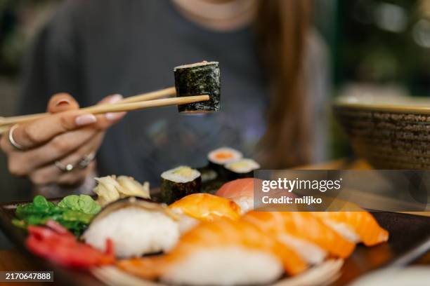 eating sushi in a restaurant - girl eating fish stock pictures, royalty-free photos & images