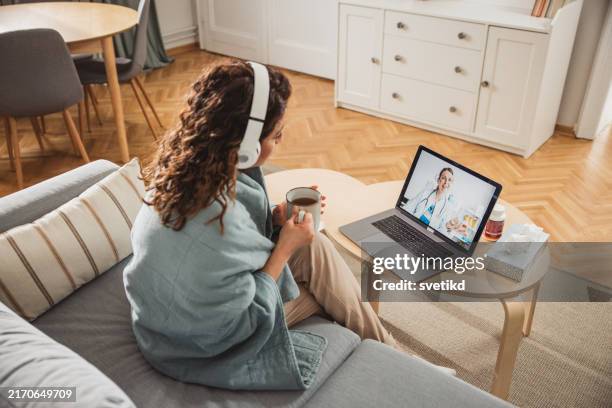 junge frau, die zu hause einen online-arzttermin hat - telemedizin stock-fotos und bilder