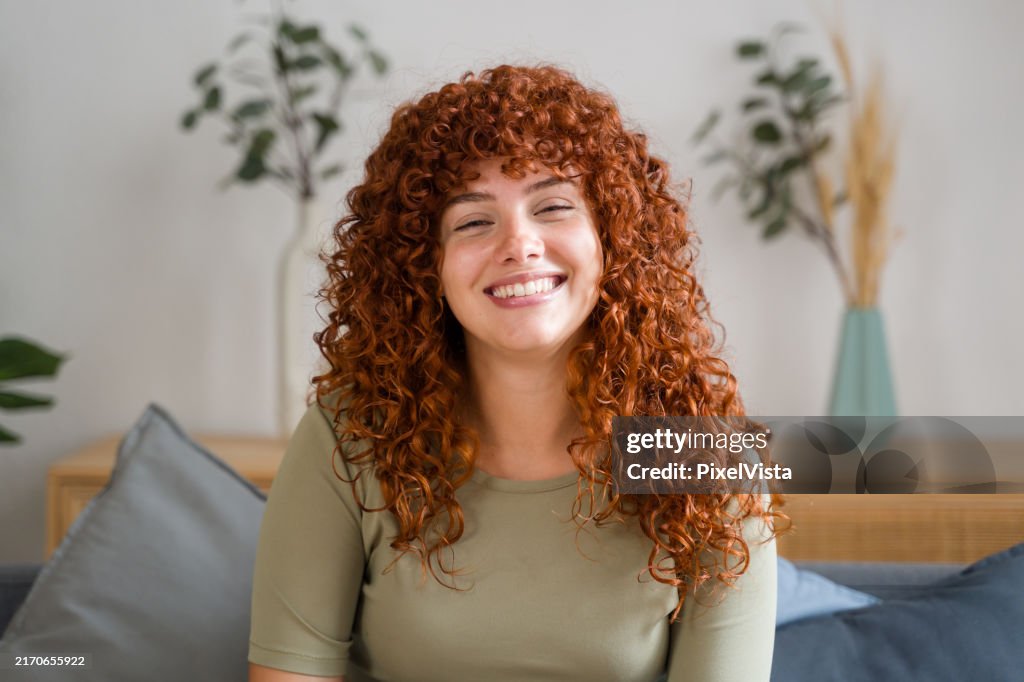 Femme aux cheveux roux souriant à la maison