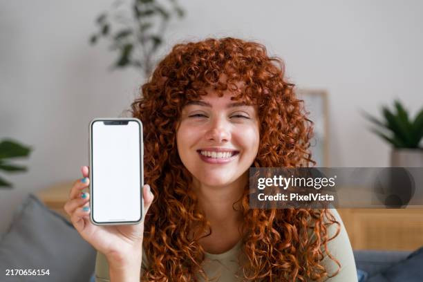 young woman showing smartphone with empty screen at home - how to stock pictures, royalty-free photos & images