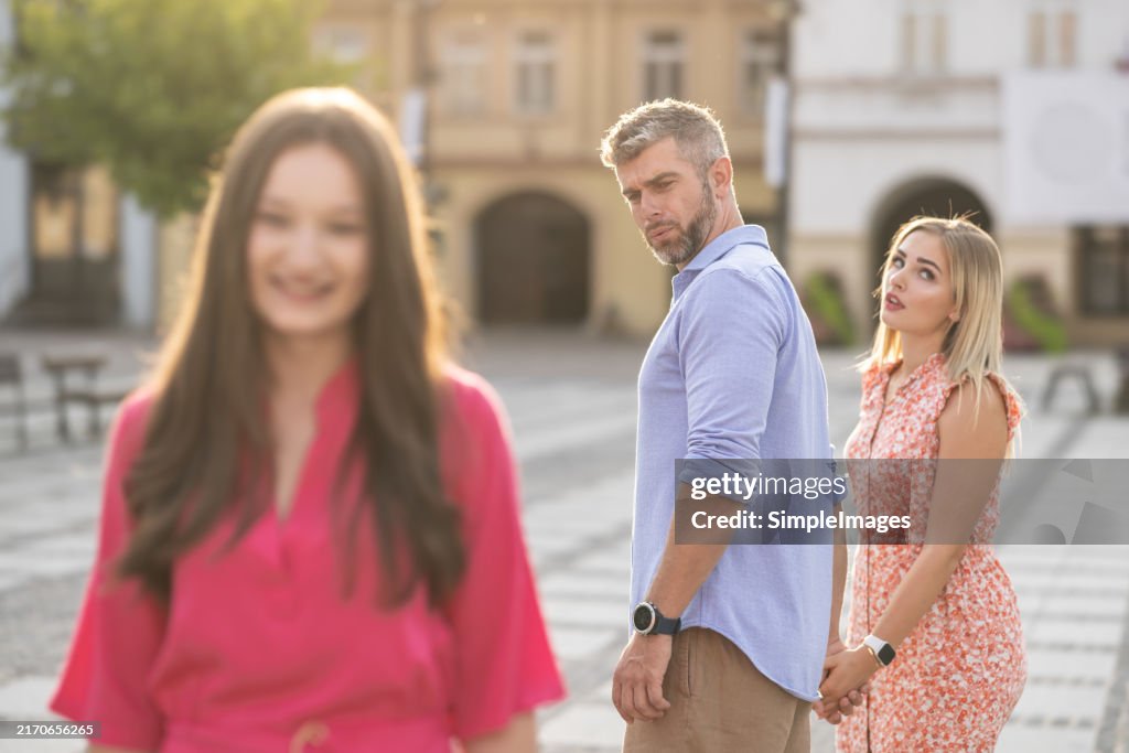 Unfaithful womanizer, a guy who turned around and admires another woman while walking down the street with his girlfriend and she is upset with him