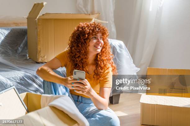 frau mit smartphone und entspannung am umzugstag - studentenwohnung stock-fotos und bilder