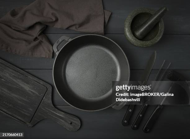 cast iron brazier, with cooking utensils, for cooking, on a dark gray, wooden table, top view, horizontal, toned - ciotola vuota foto e immagini stock