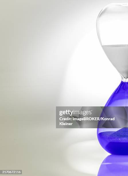 hourglass with blue sand halfway through, minimalist design with shadows and reflections - reflex hammer stock illustrations