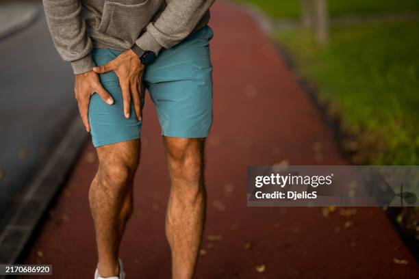 un athlète masculin méconnaissable s’est blessé à la cuisse lors d’une course en plein air. - jambe humaine photos et images de collection