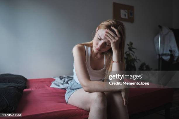 morning headache. young woman sitting on bed touching forehead suffering from headache or migraine. insomnia concept - neurotransmissor imagens e fotografias de stock