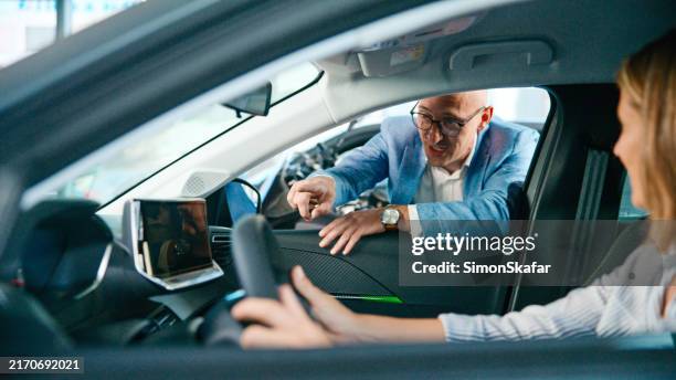 verkäufer, der eine kundin bei der probefahrt mit einem neuen auto unterstützt - testfahrt stock-fotos und bilder