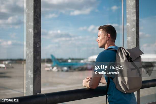 man with backpack standing in airport terminal - travel insurance stock pictures, royalty-free photos & images