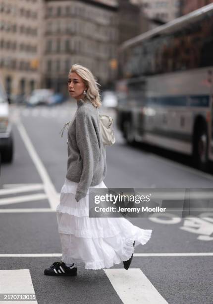 Belina Bellwood seen wearing silver hoop earrings, grey wool knit oversized sweater, Bershka white laced maxi skirt, Balenciaga white leather City...