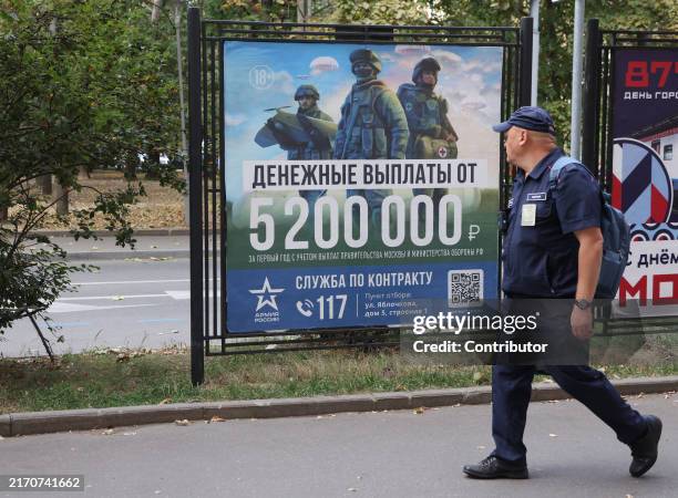 Man walks past to the billboards, showing a military propaganda of contract service in armed forces on September 11, 2024 in Moscow, Russia. The...