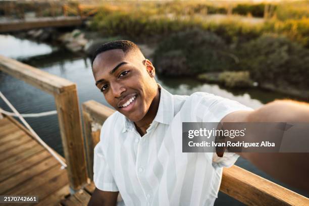 young man taking a selfie on a wooden bridge - free mms stock pictures, royalty-free photos & images
