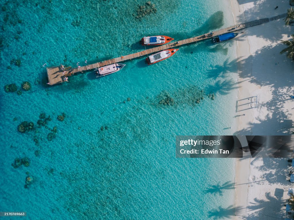 Drone point of view anchored boats at lagoon with pier in lang tengah island, malaysia