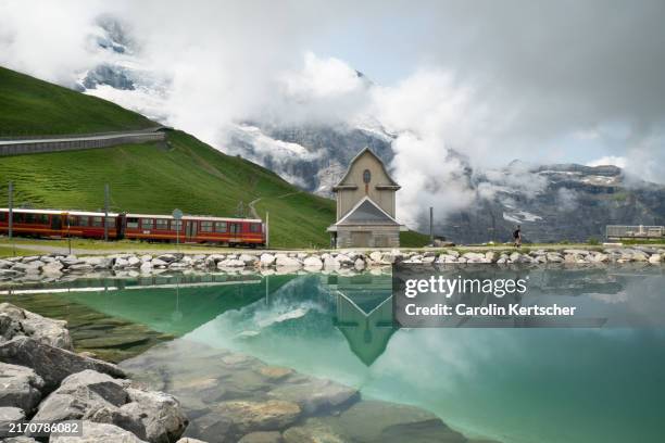 train at reservoir in the bernese alps with reflection of the mountain panorama | switzerland - jungfrau stock-fotos und bilder