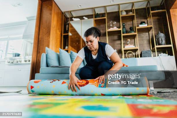 housekeeper organizing rug in the living room - domestic staff stock pictures, royalty-free photos & images