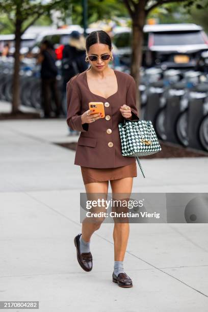 Guest wears brown jacket, skirt, black white bag outside Monse New York Fashion Week on September 07, 2024 in New York City.