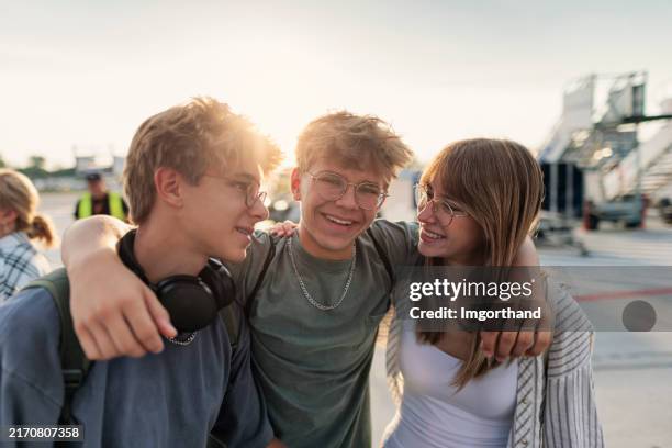 young travelers standing on airstrip waiting to board the plane. - männlicher teenager stock-fotos und bilder
