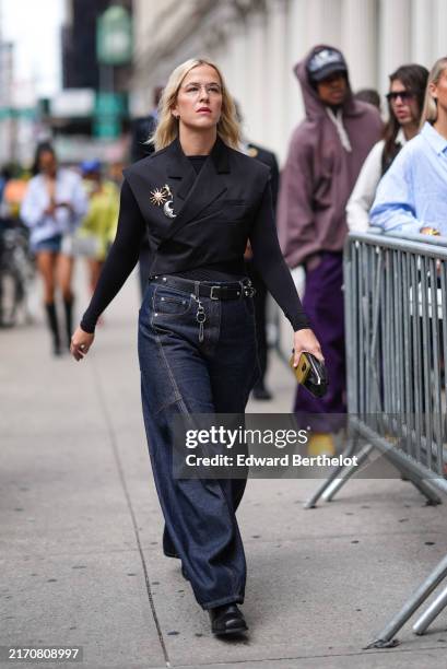 Guest wears silver rimmed sunglasses, silver earrings, black long sleeve shirt, black criss cross blazer tailored vest with sun and moon brooches,...