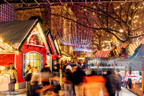 people walking among decorated market stalls at the christmas market, berlin, germany - christkindlmarkt stock-fotos und bilder