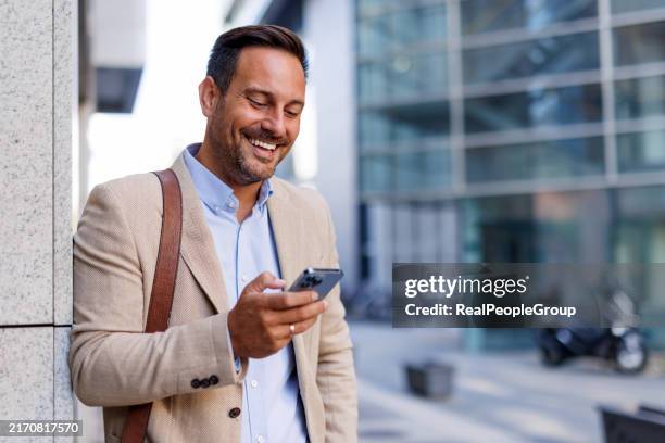 geschäftsmann mit telefon, während er auf dem bürgersteig geht - beiger anzug stock-fotos und bilder