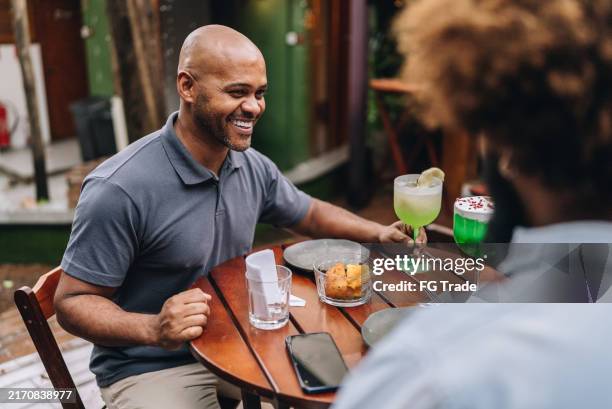 mature man talking with friend at restaurant - salgadinhos stock pictures, royalty-free photos & images