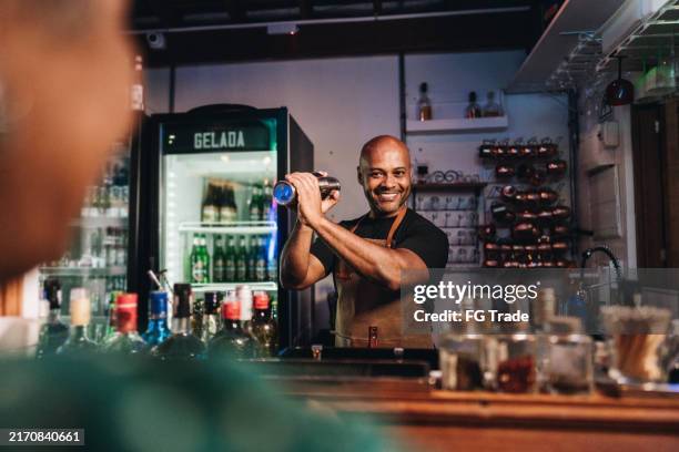 bartender preparing drink and talking with customer at pub - bartender stock pictures, royalty-free photos & images