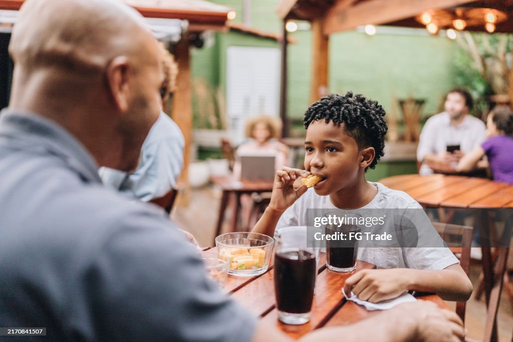 Son eating and talking with father at restaurant