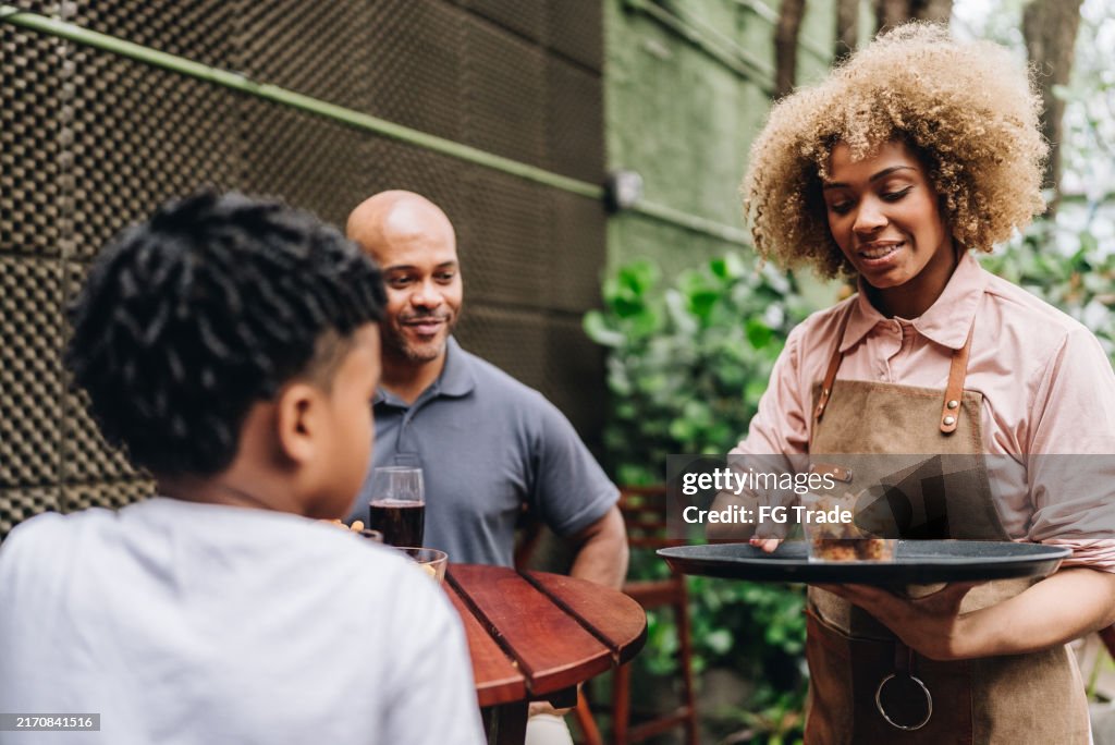 Cameriera giovane donna che serve antipasti ai clienti di un ristorante